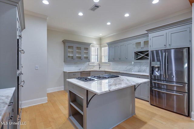 kitchen featuring stainless steel appliances, sink, a center island, light stone counters, and decorative backsplash