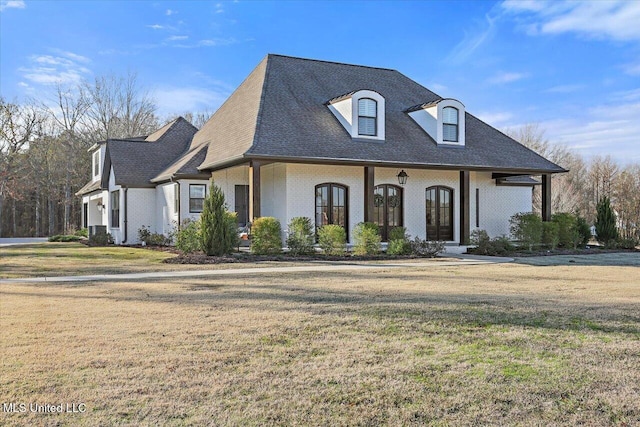 french provincial home featuring a porch, french doors, and a front yard