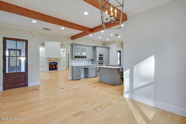 kitchen with a center island, backsplash, hanging light fixtures, gray cabinets, and a breakfast bar