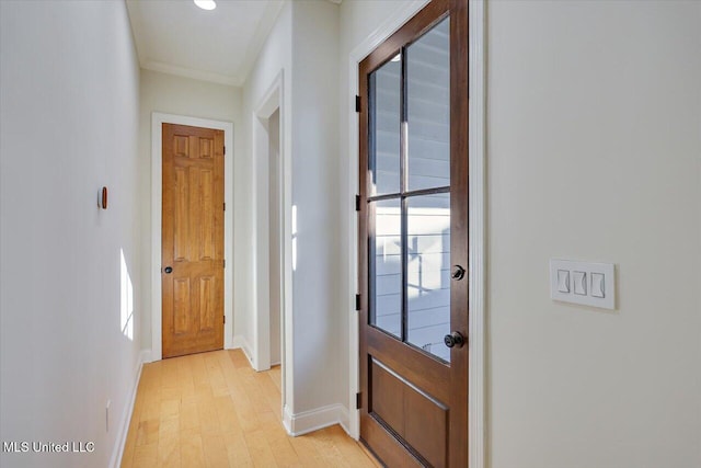 doorway with ornamental molding and light hardwood / wood-style floors