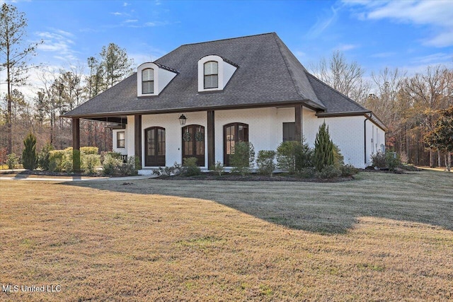 french country home featuring a porch and a front yard