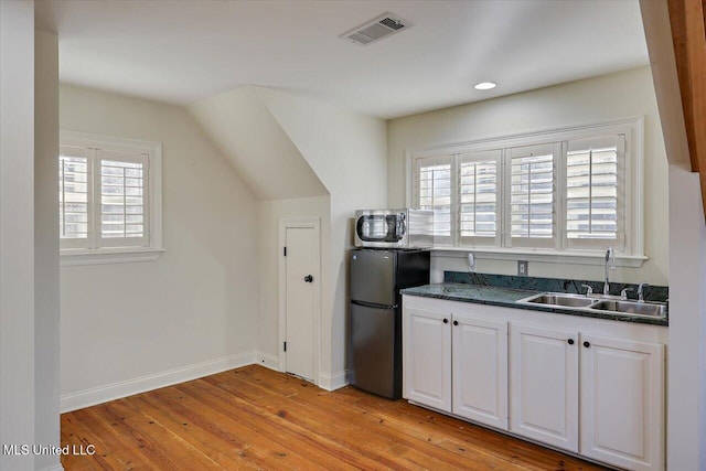 kitchen featuring sink, black refrigerator, white cabinets, and a healthy amount of sunlight