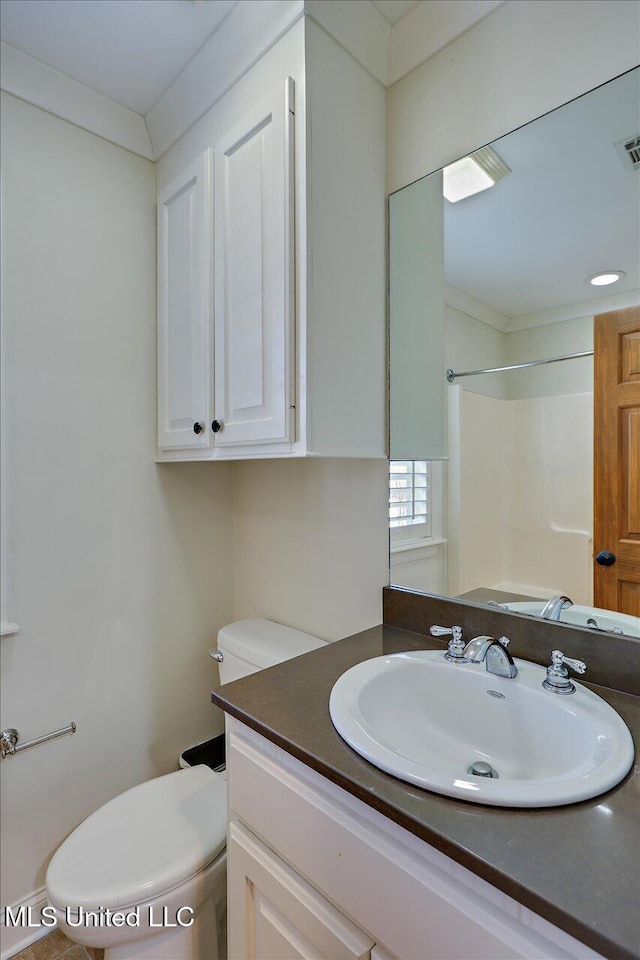 bathroom with toilet, vanity, crown molding, and walk in shower