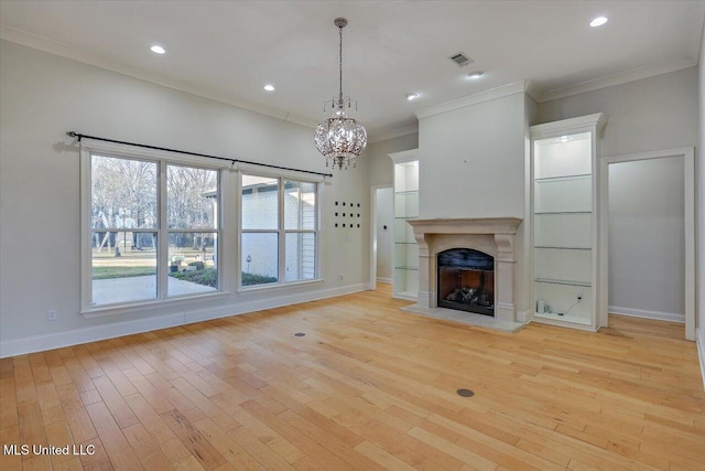 unfurnished living room with crown molding, light wood-type flooring, plenty of natural light, and a notable chandelier