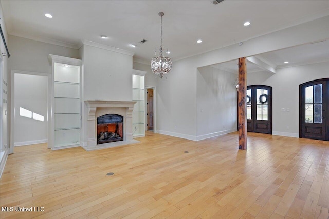 unfurnished living room featuring light wood-type flooring, a notable chandelier, and crown molding