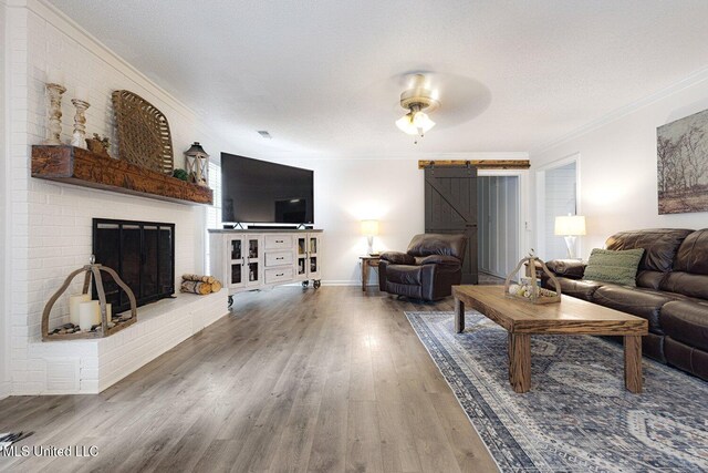 7101 Blue Grass Rd, Olive Branch, MS 38654 - living room featuring ornamental molding, wood finished floors, a barn door, a fireplace, and a textured ceiling