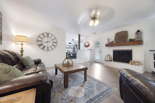 7101 Blue Grass Rd, Olive Branch, MS 38654 - living room featuring a ceiling fan, wood finished floors, ornamental molding, a brick fireplace, and a textured ceiling