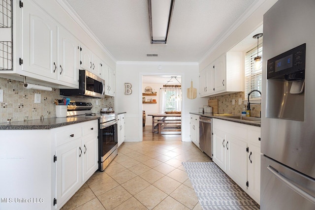 7101 Blue Grass Rd, Olive Branch, MS 38654 - kitchen with stainless steel appliances, dark countertops, tasteful backsplash, white cabinets, and ornamental molding