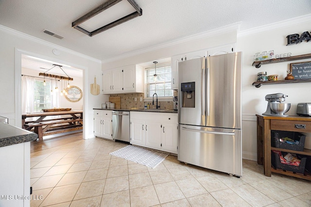 7101 Blue Grass Rd, Olive Branch, MS 38654 - kitchen with appliances with stainless steel finishes, crown molding, dark countertops, white cabinetry, and light tile patterned floors