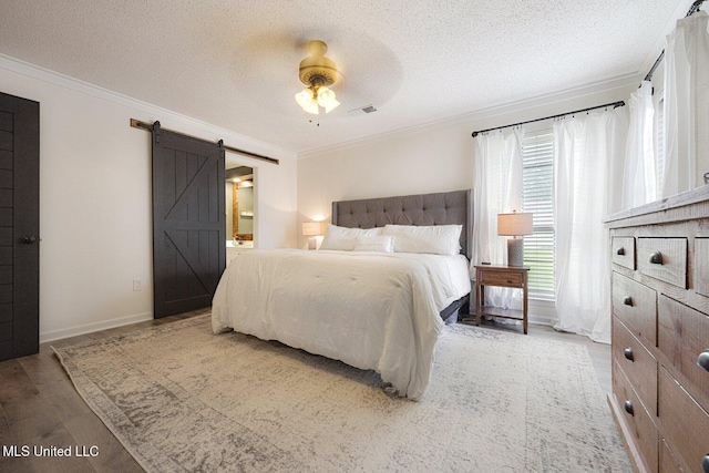 7101 Blue Grass Rd, Olive Branch, MS 38654 - bedroom with a barn door, ornamental molding, a textured ceiling, wood finished floors, and connected bathroom