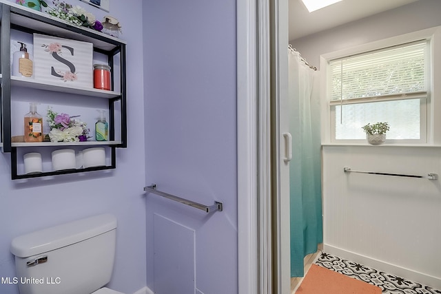 bathroom with toilet and a shower with shower curtain