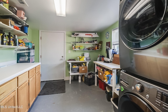 laundry room featuring cabinets and stacked washer and clothes dryer