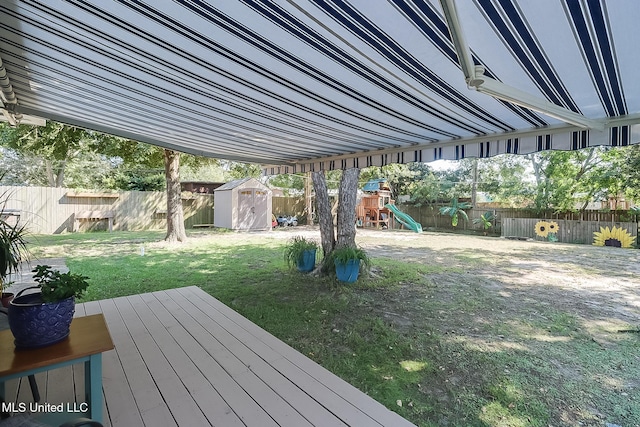 wooden deck with a shed, a lawn, and a playground