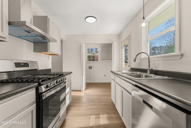 kitchen featuring pendant lighting, a textured ceiling, wall chimney exhaust hood, stainless steel appliances, and sink