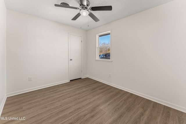 spare room with ceiling fan, dark hardwood / wood-style floors, and a textured ceiling