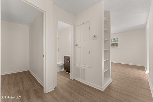 corridor with a textured ceiling and hardwood / wood-style floors