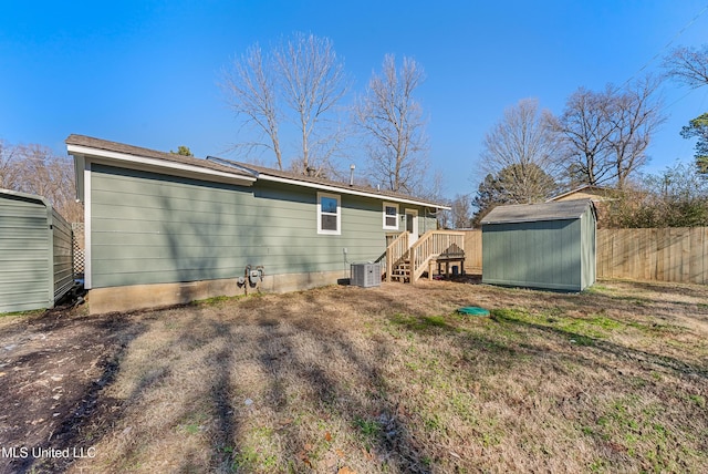 back of property with a wooden deck, central AC unit, and a storage shed