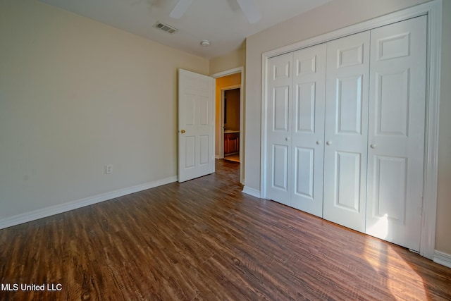 unfurnished bedroom with a closet, dark wood-style flooring, visible vents, and baseboards