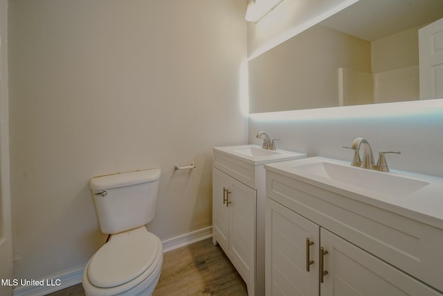 bathroom with toilet, baseboards, wood finished floors, and vanity