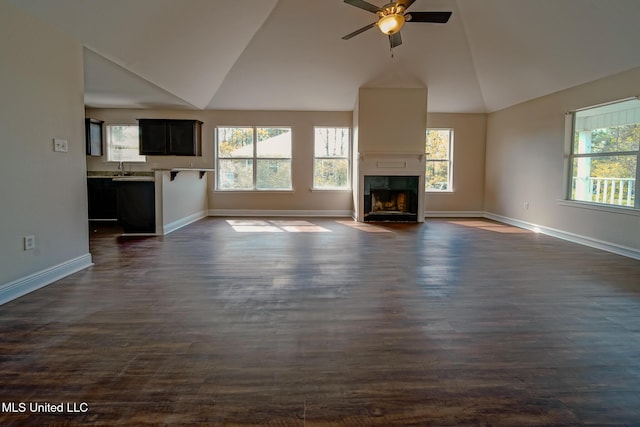 unfurnished living room featuring vaulted ceiling, dark wood-type flooring, and a healthy amount of sunlight