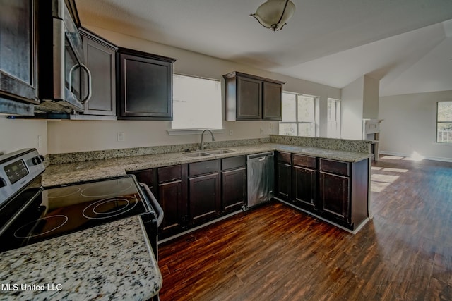 kitchen with a peninsula, appliances with stainless steel finishes, dark wood-type flooring, and a sink