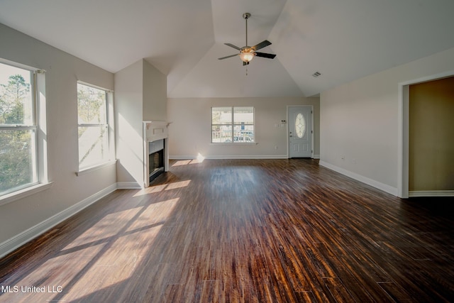 unfurnished living room with a wealth of natural light, a fireplace with flush hearth, dark wood finished floors, and baseboards