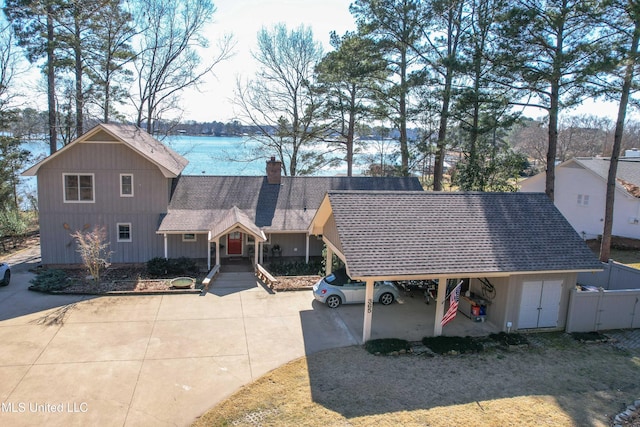 view of front of property with concrete driveway, a shingled roof, and a chimney