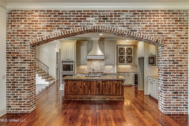 2024 E Northside Dr, Jackson, MS 39211 - kitchen featuring premium range hood, cream cabinetry, appliances with stainless steel finishes, and dark wood-type flooring
