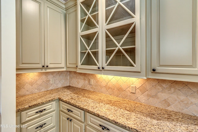 2024 E Northside Dr, Jackson, MS 39211 - kitchen featuring light stone countertops, glass insert cabinets, decorative backsplash, and cream cabinets