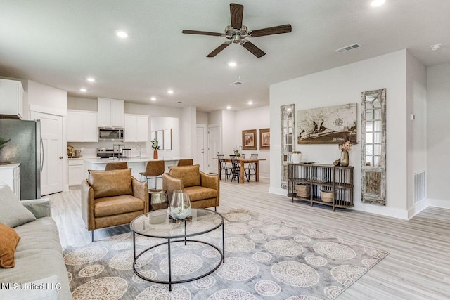 living area featuring light wood-style flooring and visible vents