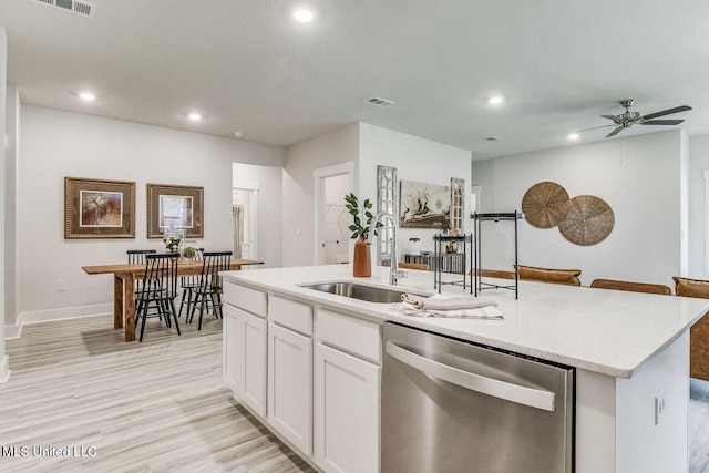 kitchen featuring visible vents, a kitchen island with sink, white cabinetry, a sink, and dishwasher