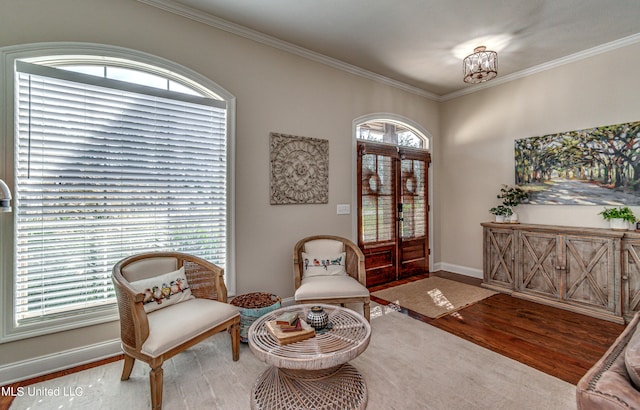 living area featuring ornamental molding, wood-type flooring, and plenty of natural light