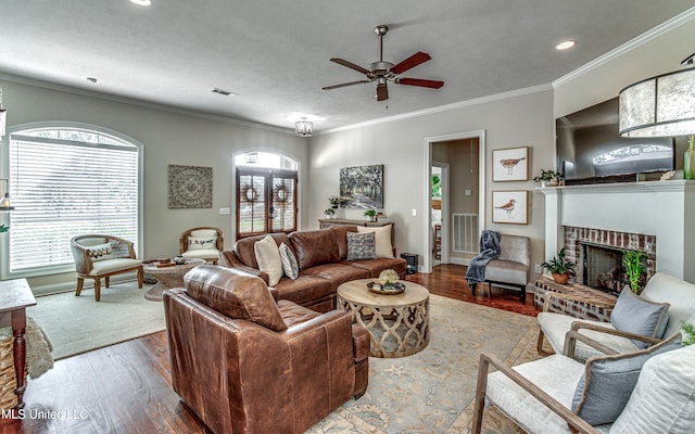 living room with a healthy amount of sunlight, ornamental molding, a fireplace, and hardwood / wood-style floors