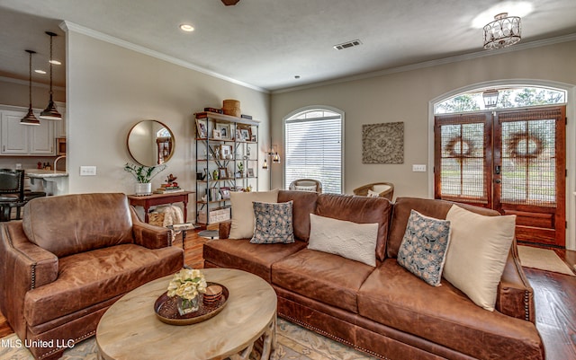 living room featuring ornamental molding, light hardwood / wood-style floors, a notable chandelier, french doors, and sink