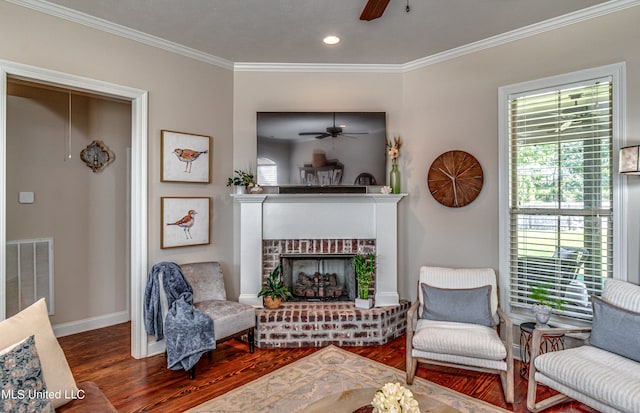 living room with crown molding, hardwood / wood-style flooring, a fireplace, and ceiling fan