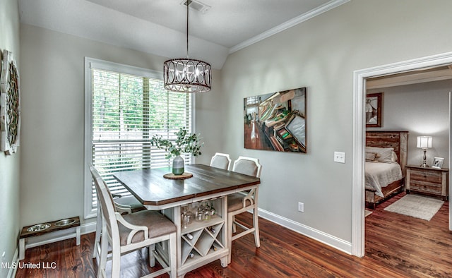 dining area with an inviting chandelier, ornamental molding, lofted ceiling, and dark hardwood / wood-style flooring