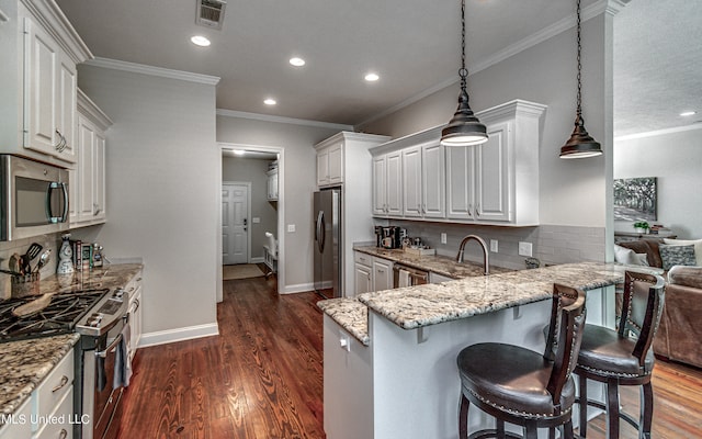 kitchen with dark hardwood / wood-style flooring, a kitchen breakfast bar, white cabinetry, stainless steel appliances, and decorative light fixtures