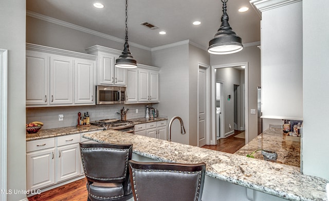 kitchen with white cabinetry, pendant lighting, stainless steel appliances, and a kitchen bar