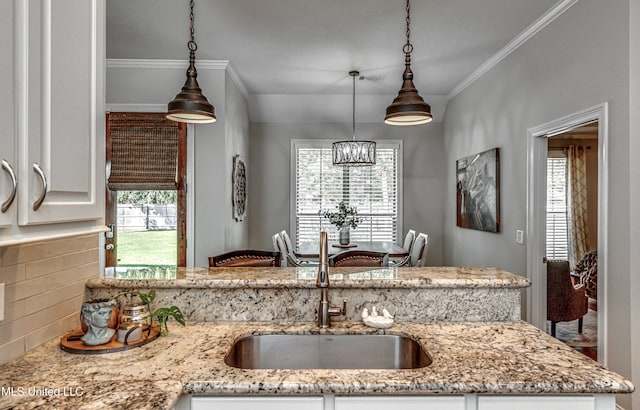 kitchen with crown molding, sink, pendant lighting, and white cabinets