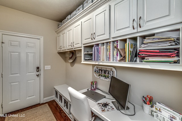 home office with a textured ceiling and dark hardwood / wood-style floors