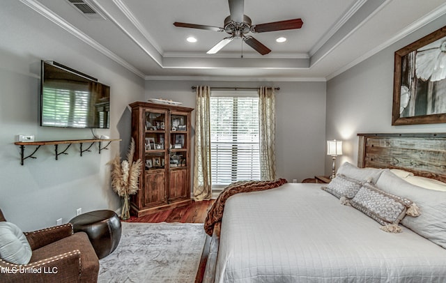 bedroom with ceiling fan, hardwood / wood-style flooring, ornamental molding, and a tray ceiling