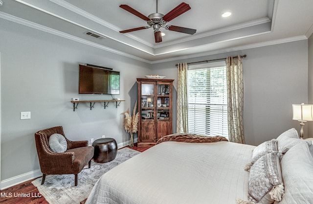 bedroom with ceiling fan, hardwood / wood-style flooring, ornamental molding, and a tray ceiling