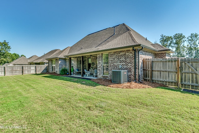 rear view of property with a patio, cooling unit, and a yard