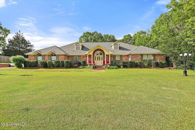 view of front of home featuring a shingled roof, a front lawn, and brick siding