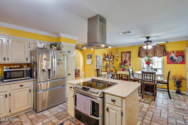 kitchen featuring visible vents, ceiling fan, island range hood, light countertops, and appliances with stainless steel finishes