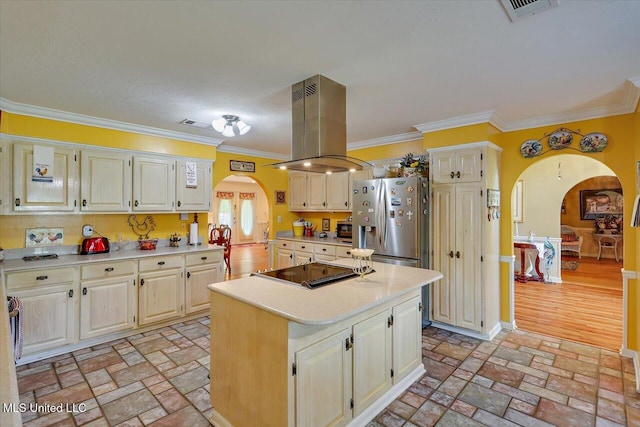 kitchen with island exhaust hood, visible vents, arched walkways, light countertops, and black electric stovetop