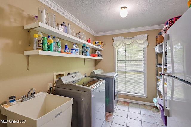 laundry room with laundry area, ornamental molding, washing machine and dryer, a textured ceiling, and a sink