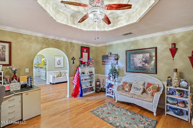 interior space with crown molding, a ceiling fan, arched walkways, and wood finished floors