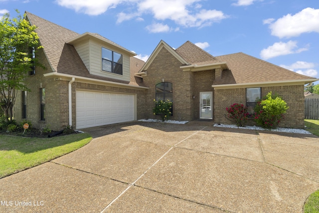 traditional-style home featuring roof with shingles, concrete driveway, an attached garage, and brick siding