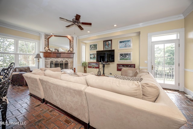 living area with a ceiling fan, plenty of natural light, crown molding, and brick floor